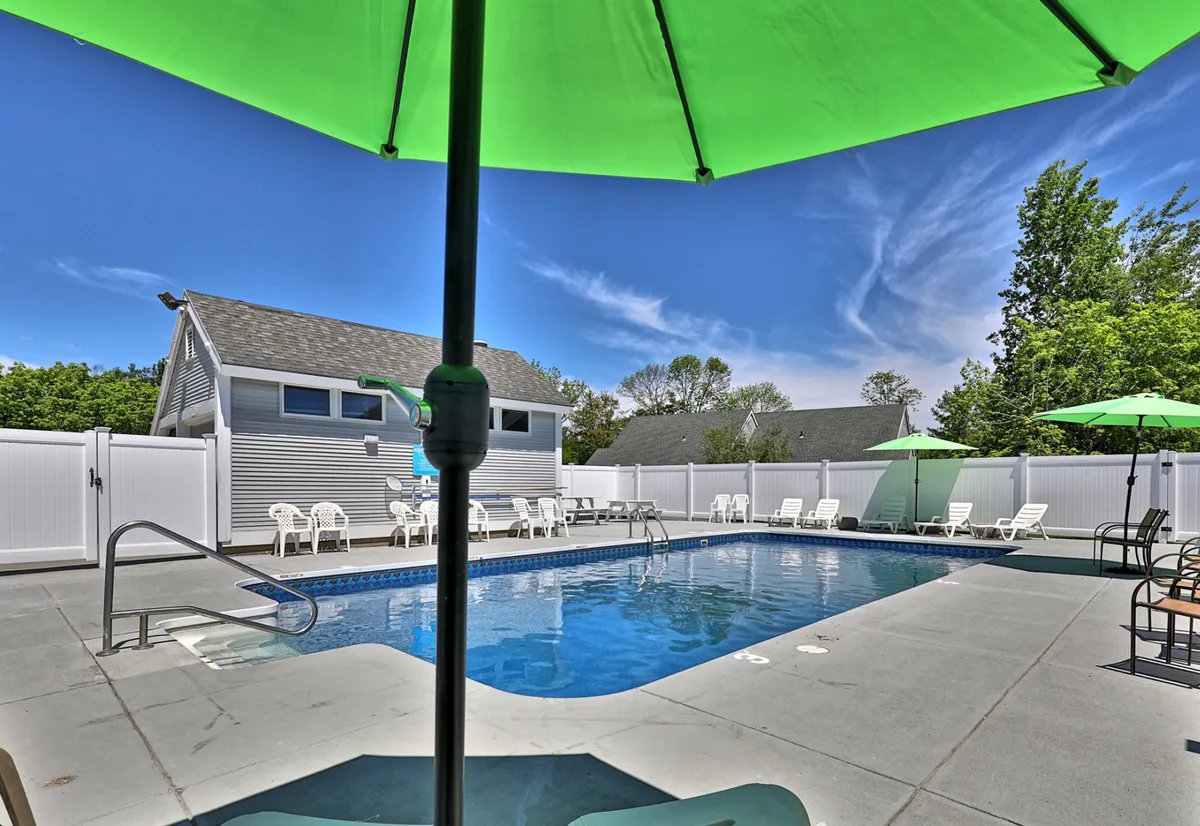 The photo highlights an outdoor swimming pool area with green umbrellas and patio chairs, presenting a vibrant spot for relaxation and socializing. The pool area looks well-maintained and inviting, suggesting extra value for guests.