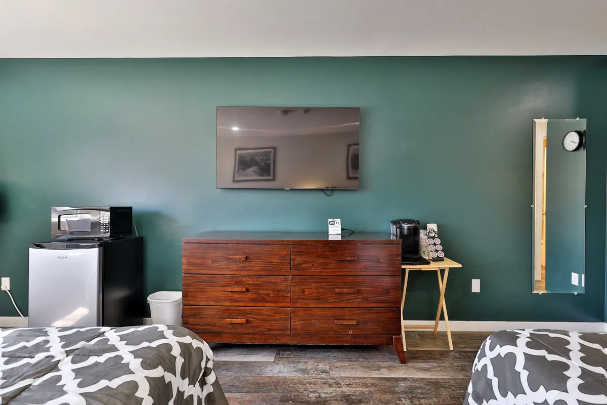 A neat corner of the studio featuring a wooden dresser, flat-screen TV, microwave, and coffee maker—essentials for preparing a quick snack or morning coffee before heading out.