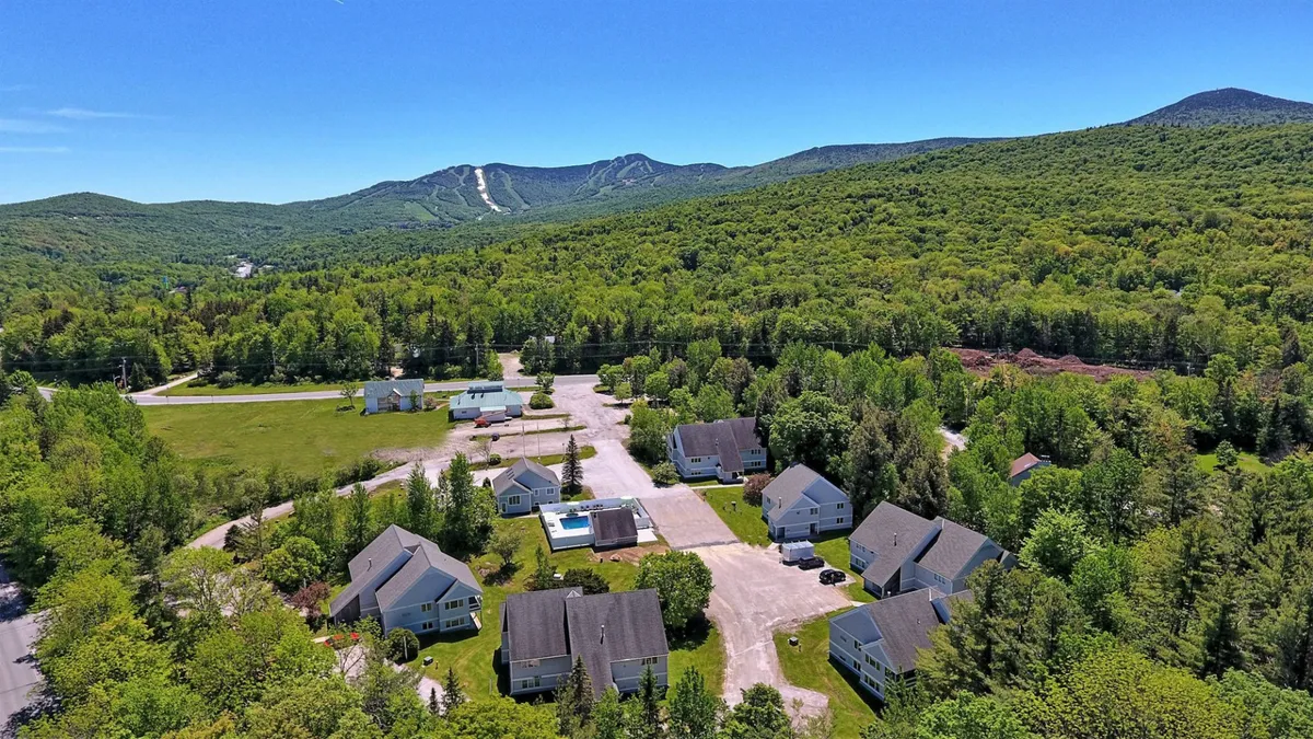 This exterior image captures a cluster of homes set against a dramatic mountain backdrop, with a clear view of the swimming pool area in the foreground. The surroundings evoke a sense of adventure and tranquility, inviting guests to explore the natural environment while also providing visual access to the pool.