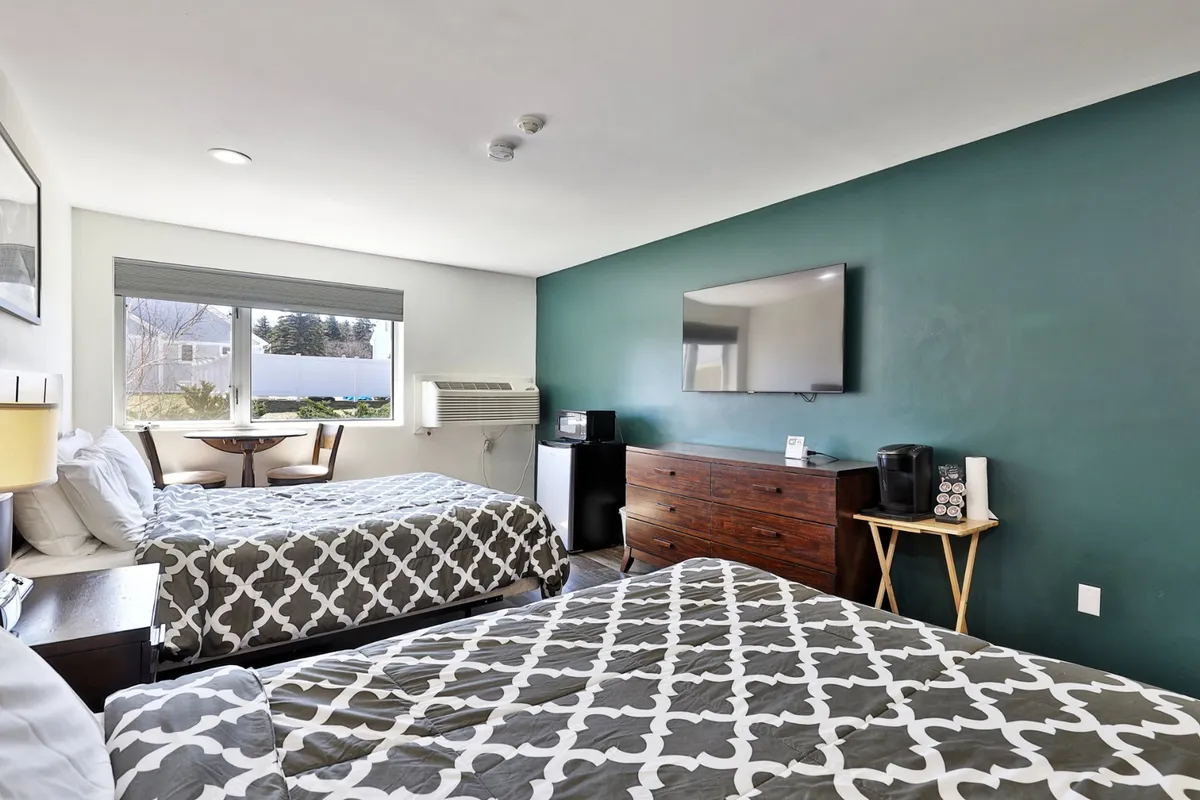 Inside the studio, two inviting beds are set beside a window that lets in natural light, with a television and dresser completing the space. The room exudes comfort and warmth, offering a welcoming retreat after a day of adventure.